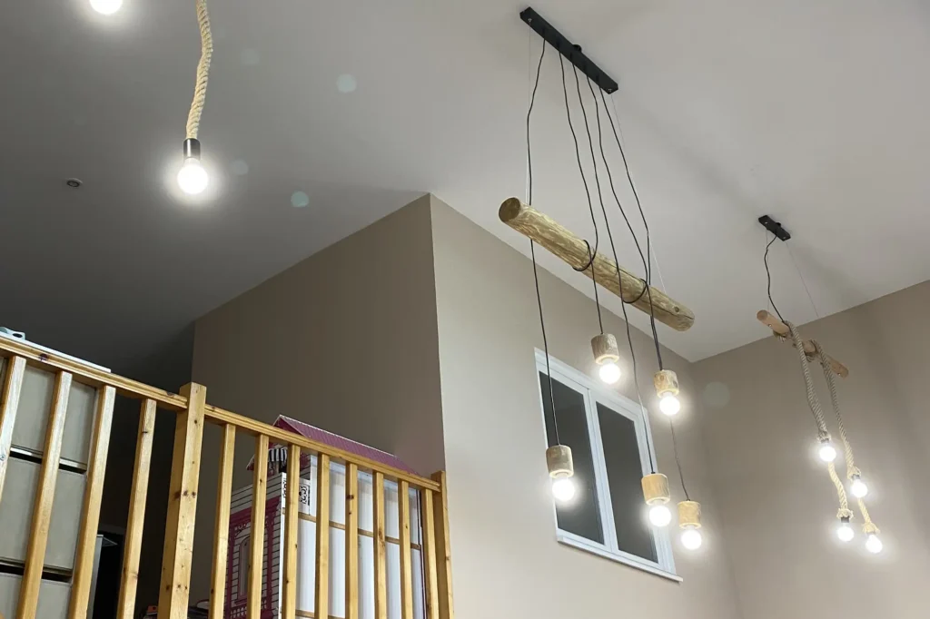 Une image montrant un intérieur en construction avec des lumières suspendues modernes et une structure en bois apparente